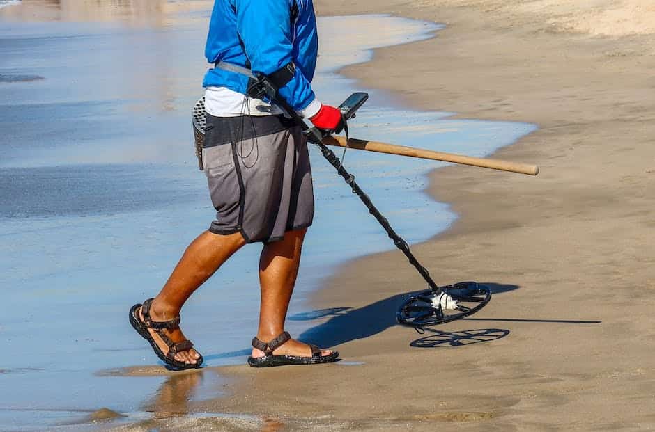 A person holding a metal detector and a shovel, searching for treasure in a field